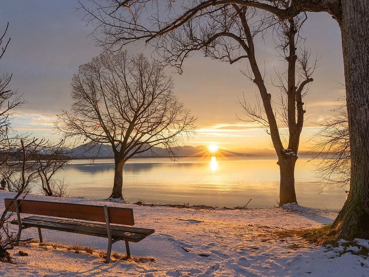 Il sole basso illumina la superficie cristallina del lago sotto il ghiaccio